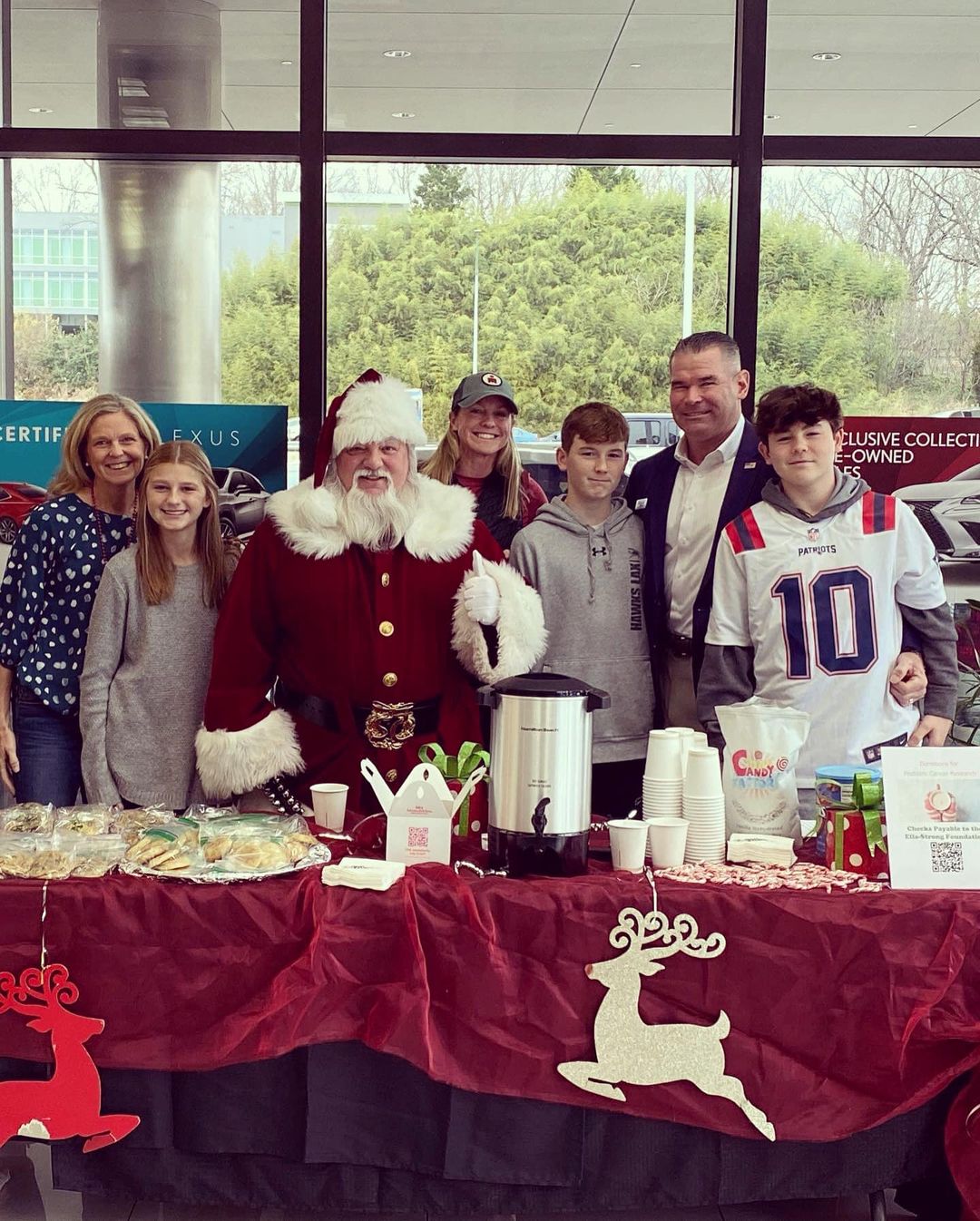 The family with Santa behind a holiday table collecting donations for pediatric cancer research