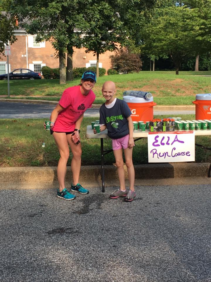 Ella handing out Gatorade at a table marked Ella Run Course