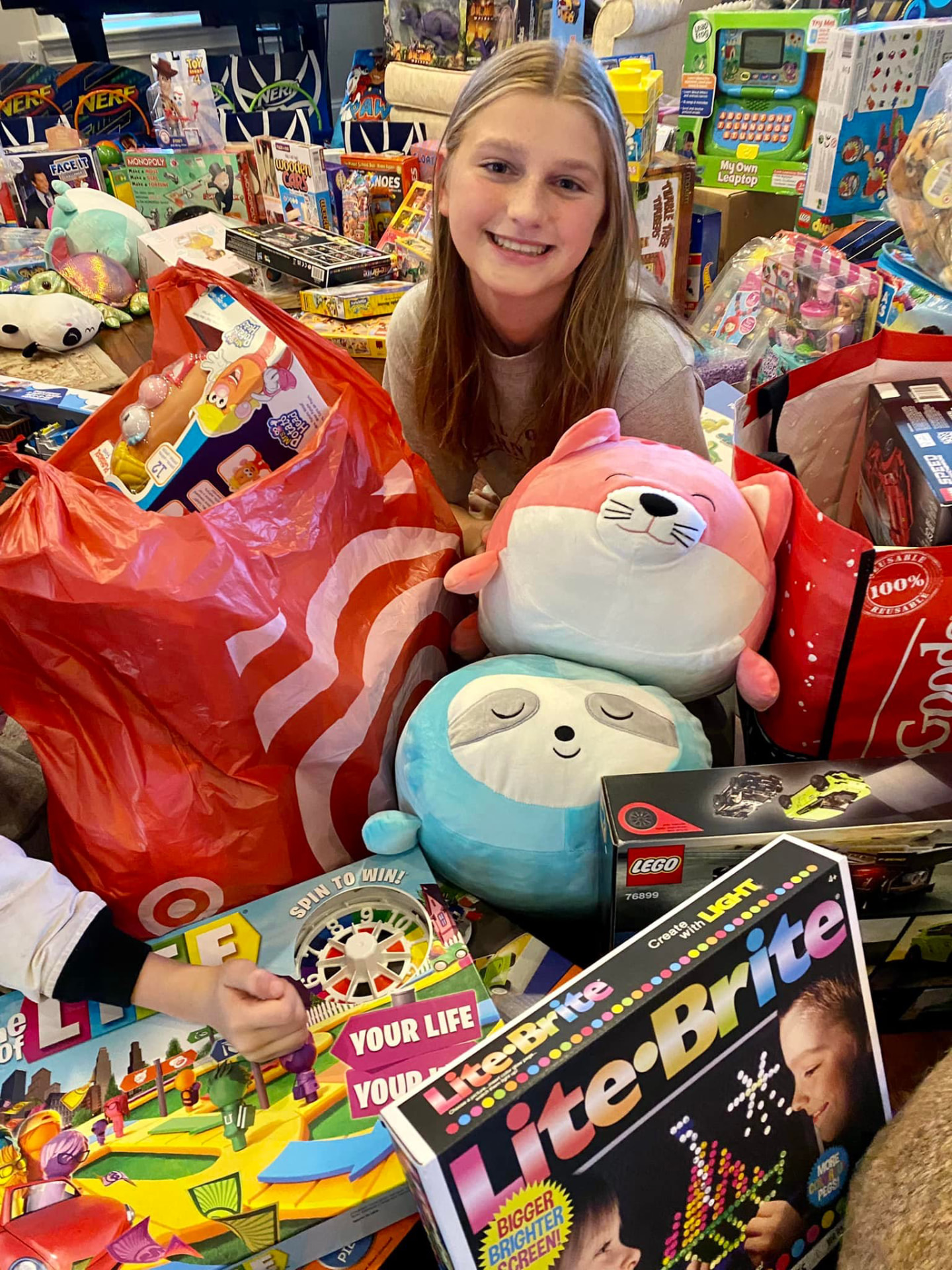 Ella surrounded by donated toys, games and stuffed animals from the toy drive