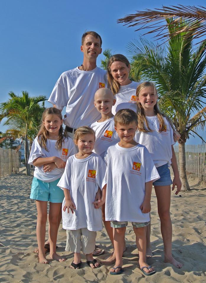 Ella with her parents and four siblings on the beach in matching white shirts